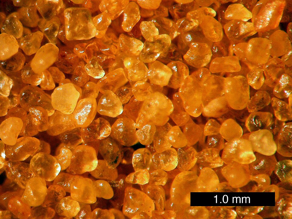 Grains de sable de quartz recouverts d'hématite, leur donnant une couleur orange.
