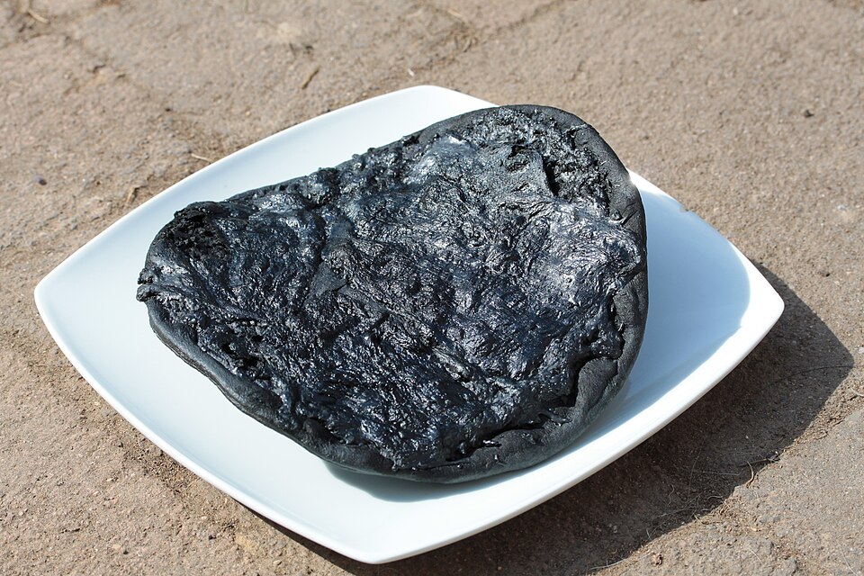Un disque noirci et tordu, à peine reconnaissable comme une pizza, se dressant raide sur une assiette (blanche et fraîche).