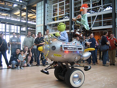 Le Muppet Mobile Lab des studios Pixar, avec deux Muppets, Honeydew et Beaker. Pete Docter, le directeur créatif de Pixar, est visible au-dessus des phares du véhicule.