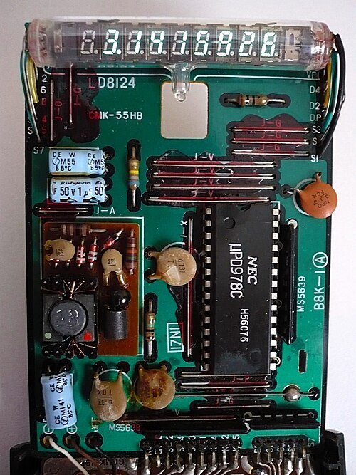 L'intérieur d'une calculatrice scientifique Casio fx-20 du milieu des années 1970, utilisant un variateur de fréquence. Le circuit intégré du processeur (CI) est fabriqué par NEC (marqué μPD978C). Les composants électroniques discrets tels que les condensateurs et les résistances et le CI sont montés sur une carte de circuit imprimé (PCB). Cette calculatrice utilise une batterie comme source d'alimentation.