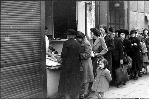 Scène de rue avec des gens faisant la queue devant un magasin