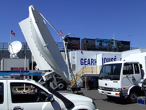 Tournoi de tennis en extérieur : camionnette de production à parois extensibles, antennes paraboliques, camion générateur ; voir deux caméras de reportage et trois cabines d'annonce au sommet du stade. Kooyong, Victoria, Australie, 2008