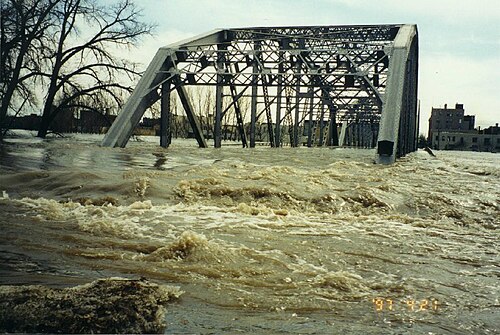 Des eaux de crue sales s'écoulent sur la chaussée d'un pont.