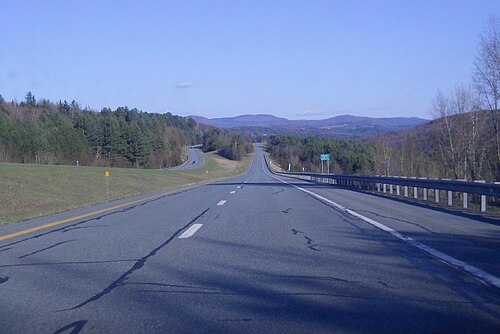 Une autoroute à quatre voies dans les bois avec vue sur les montagnes par une journée ensoleillée.