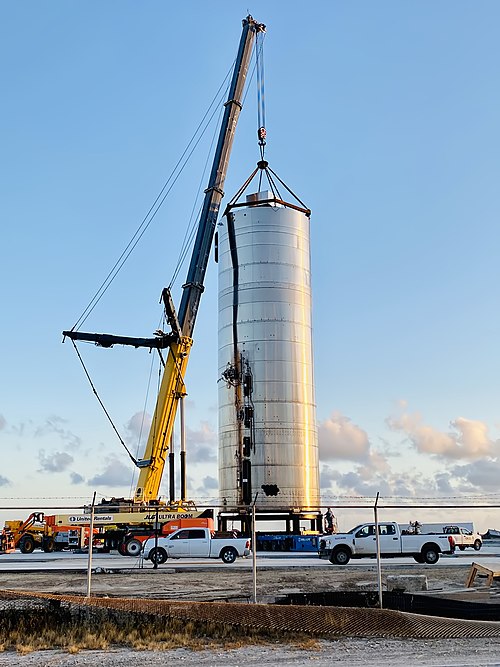 Photographie d'une grue s'accrochant à la coque d'un navire en acier