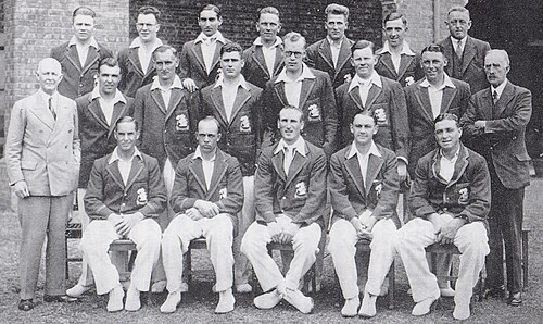 Une équipe de cricket disposée sur trois rangées. Dix-sept hommes sont habillés en joueurs, les trois autres hommes sont en costume.
