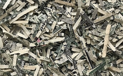 Fragments de billets de dollars américains impropres à la circulation, d'une taille typique inférieure à 1,5 mm × 16 mm