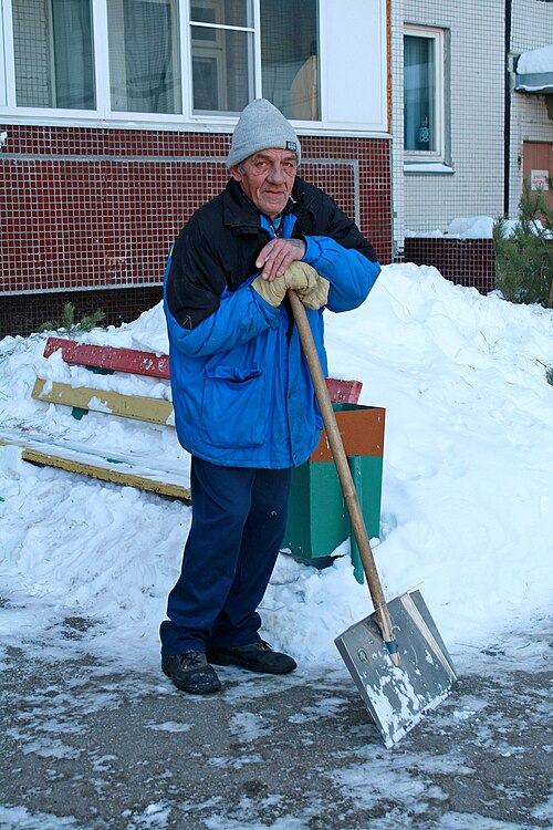 Un nettoyeur pelletant la neige des trottoirs.