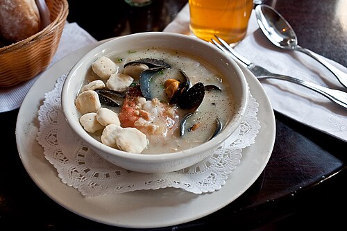Une chaudrée de fruits de mer à la crème dans un restaurant, servie avec des craquelins aux huîtres dans le bol à gauche