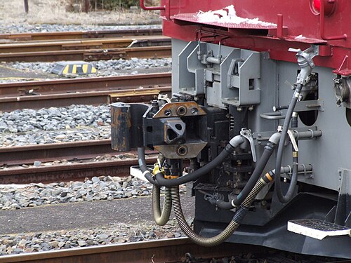JNR Class EF81, l'attelage AAR à droite (côté éloigné) de l'attelage Shibata. L'attelage Janney est représenté en position sur la ligne centrale et l'attelage Shibata est représenté comme étant écarté. Il y a un pivot en commun permettant aux deux de pivoter.