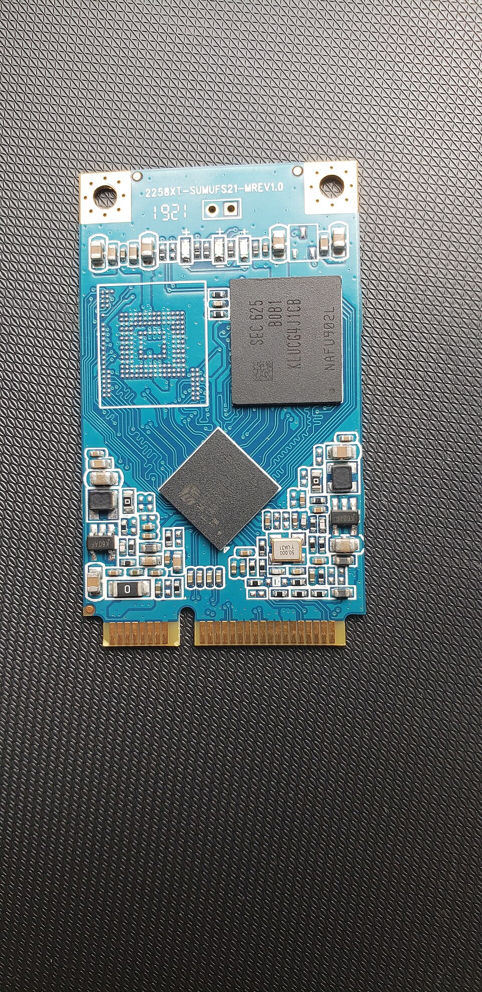 SSD mSATA dont l'étiquette a été retirée pour révéler sa mémoire NAND et son contrôleur.