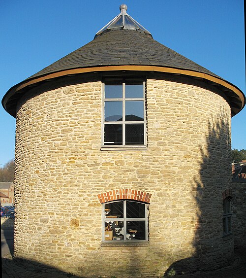Bâtiment circulaire en pierre avec toiture en ardoise.