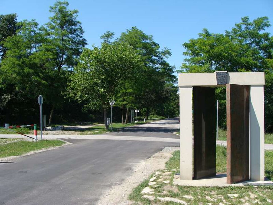 Route bordée d'arbres avec portails et poste de garde