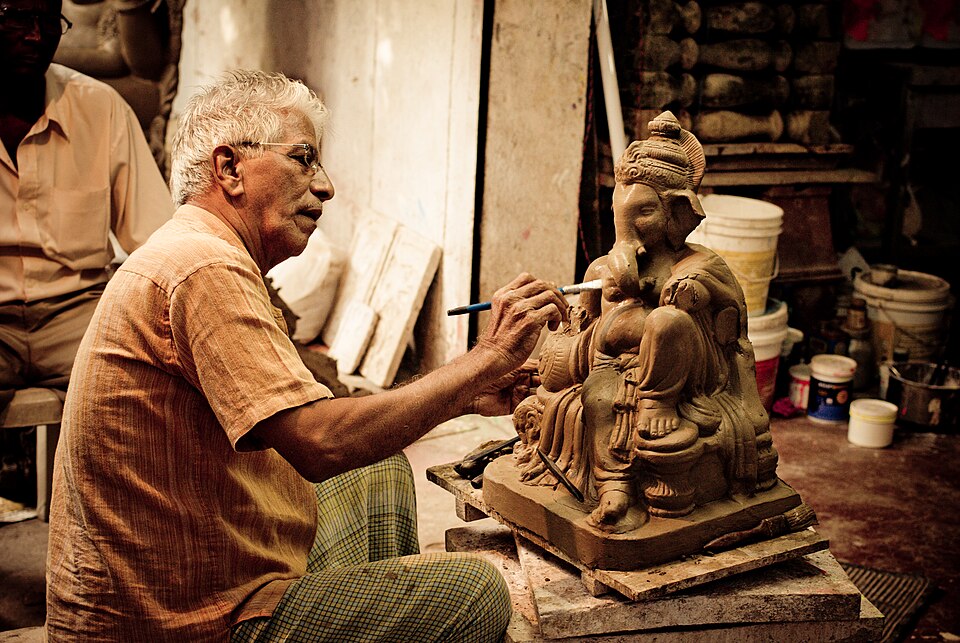 Un homme peignant une murti de Ganesh