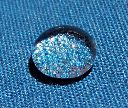 Une goutte d'eau sphérique brillante sur un tissu bleu