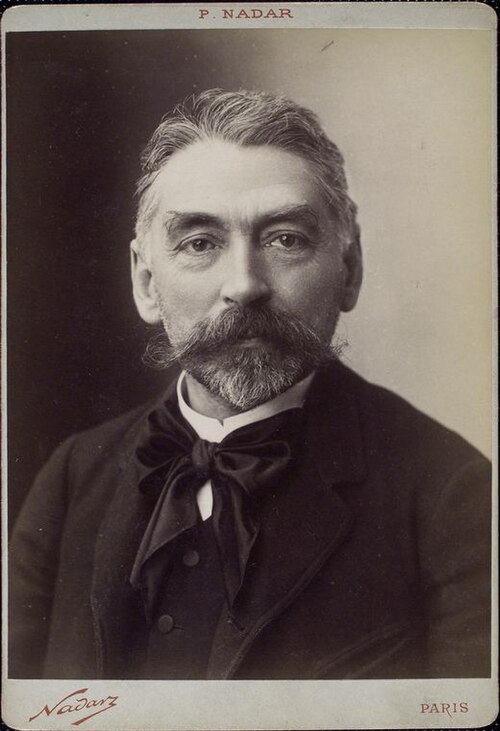 photographie de la tête et des épaules d'un homme blanc d'âge moyen avec une barbe soignée et une tête pleine de cheveux grisonnants