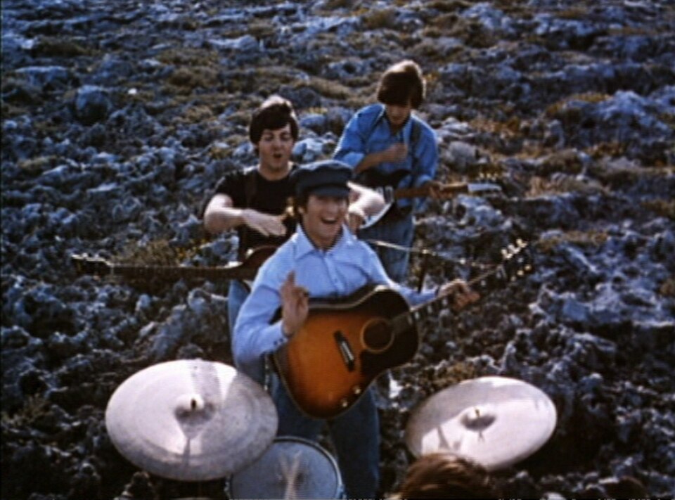 Les Beatles jouent de la musique dans un champ. Au premier plan, Starr joue de la batterie (on ne voit que le haut de sa tête). Derrière lui, les trois autres sont alignés, guitares à la main. À l'arrière, Harrison, la tête baissée, joue un accord. Au premier plan, Lennon sourit et fait un petit signe de la main à la caméra, son médiator à la main. Entre eux, McCartney fait mine d'étrangler Lennon en plaisantant.